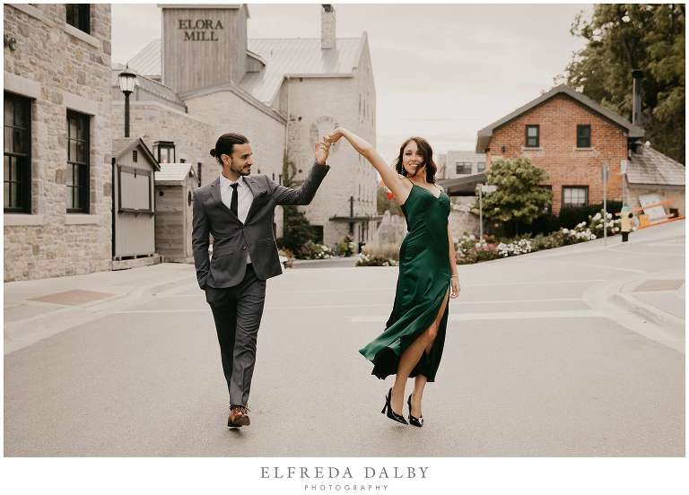 Engaged couple dancing in front of the Elora Mill