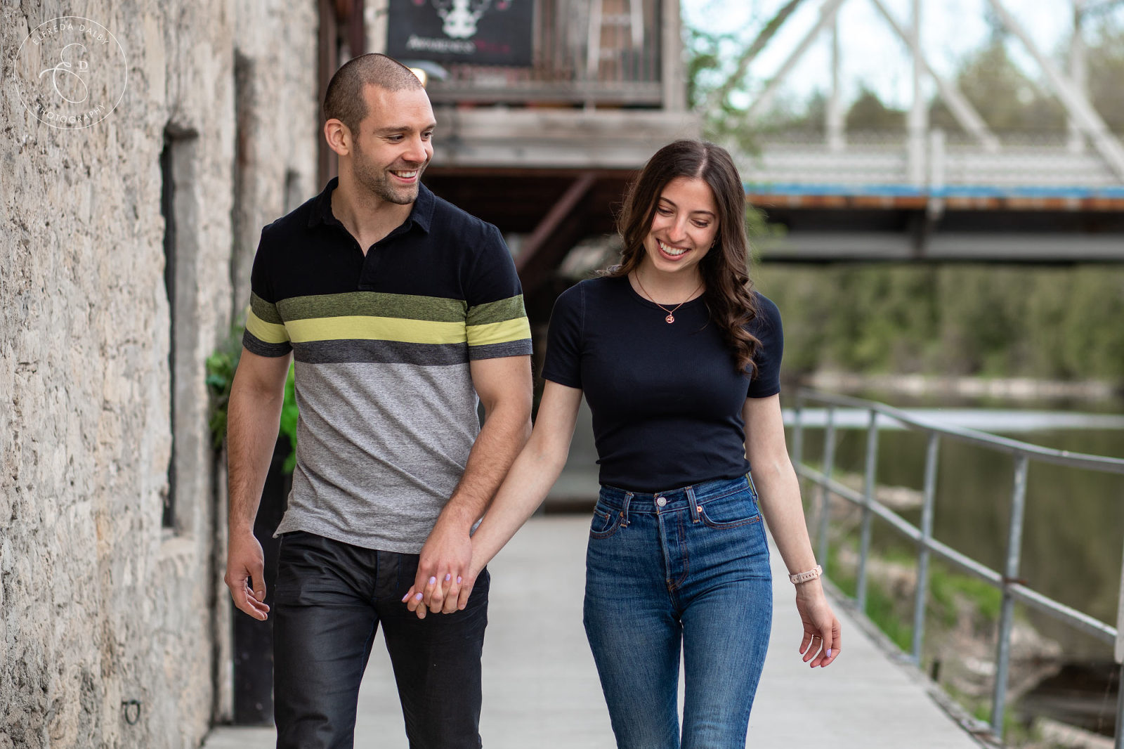 Engaged couple walking along the deck at river