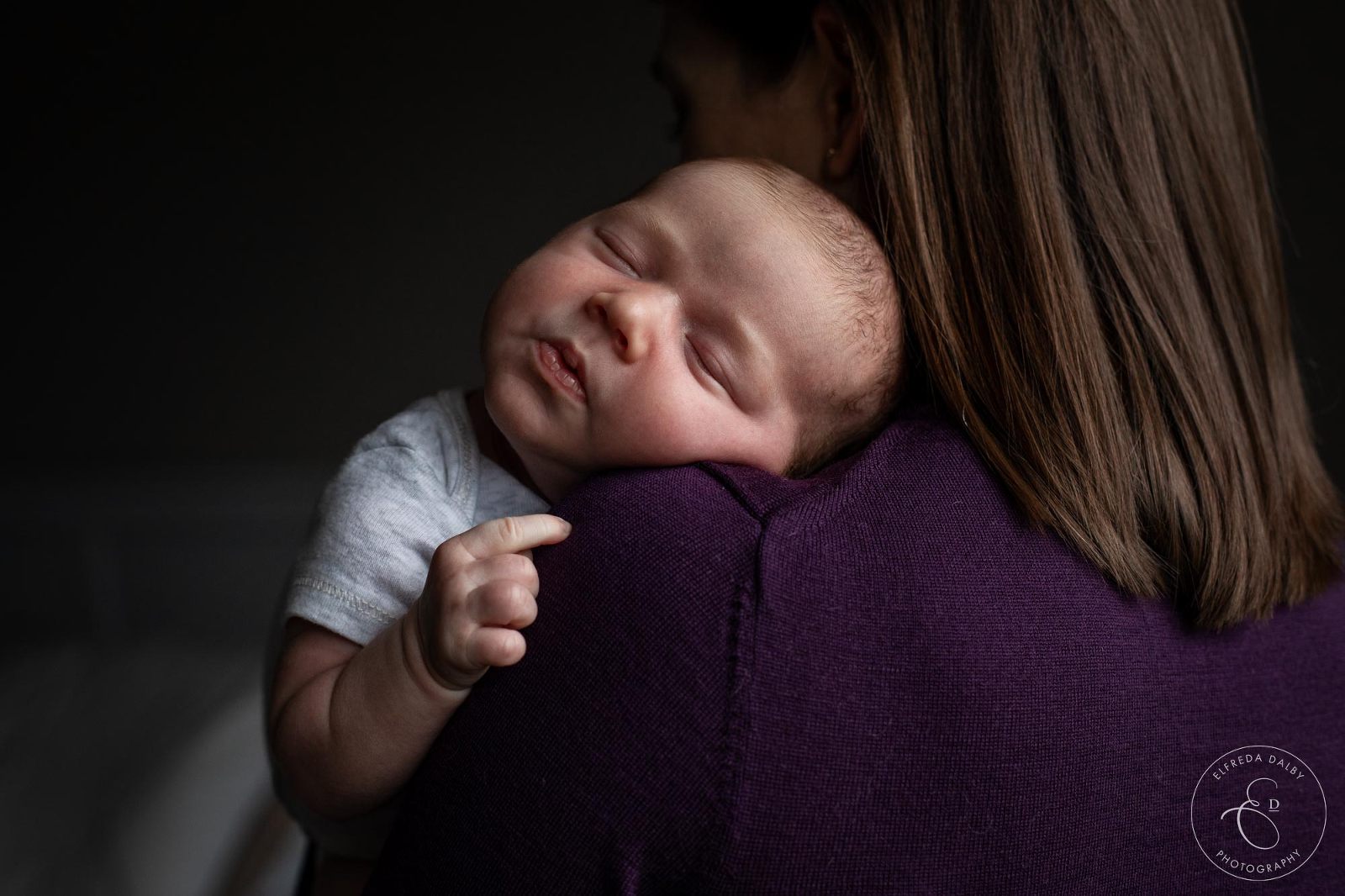 Newborn baby leaning on his mother's shoulder