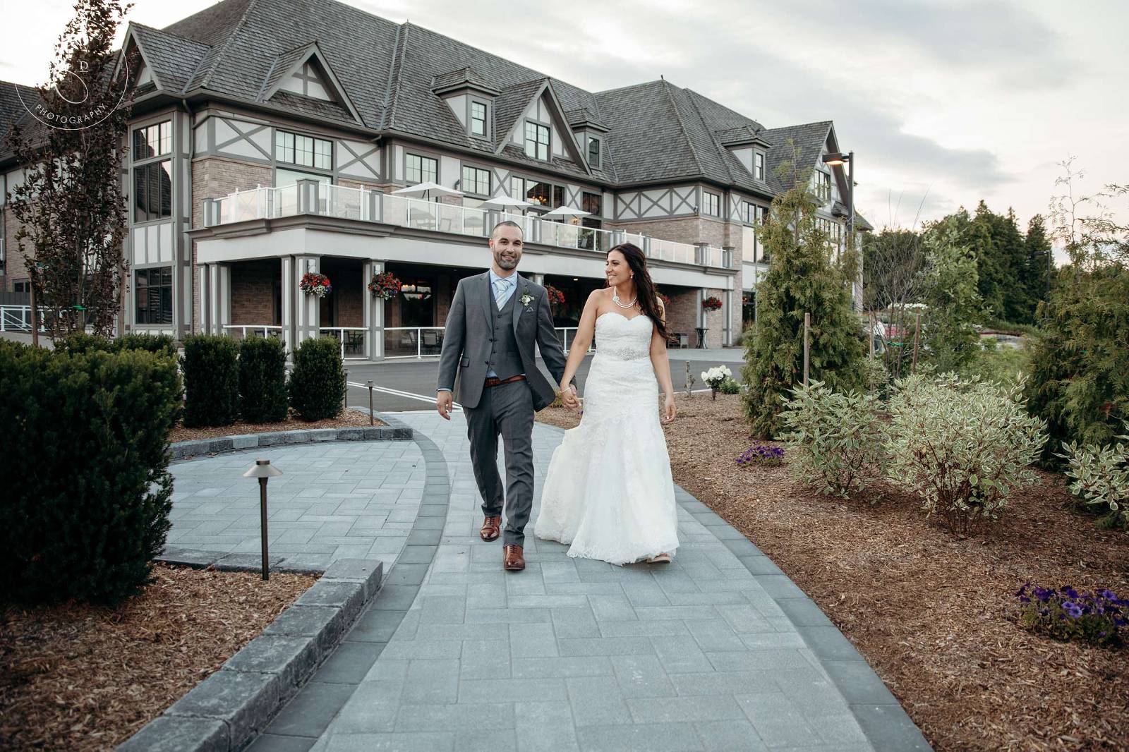Bride and Groom walk in front of the Deer Creek Golf Club building
