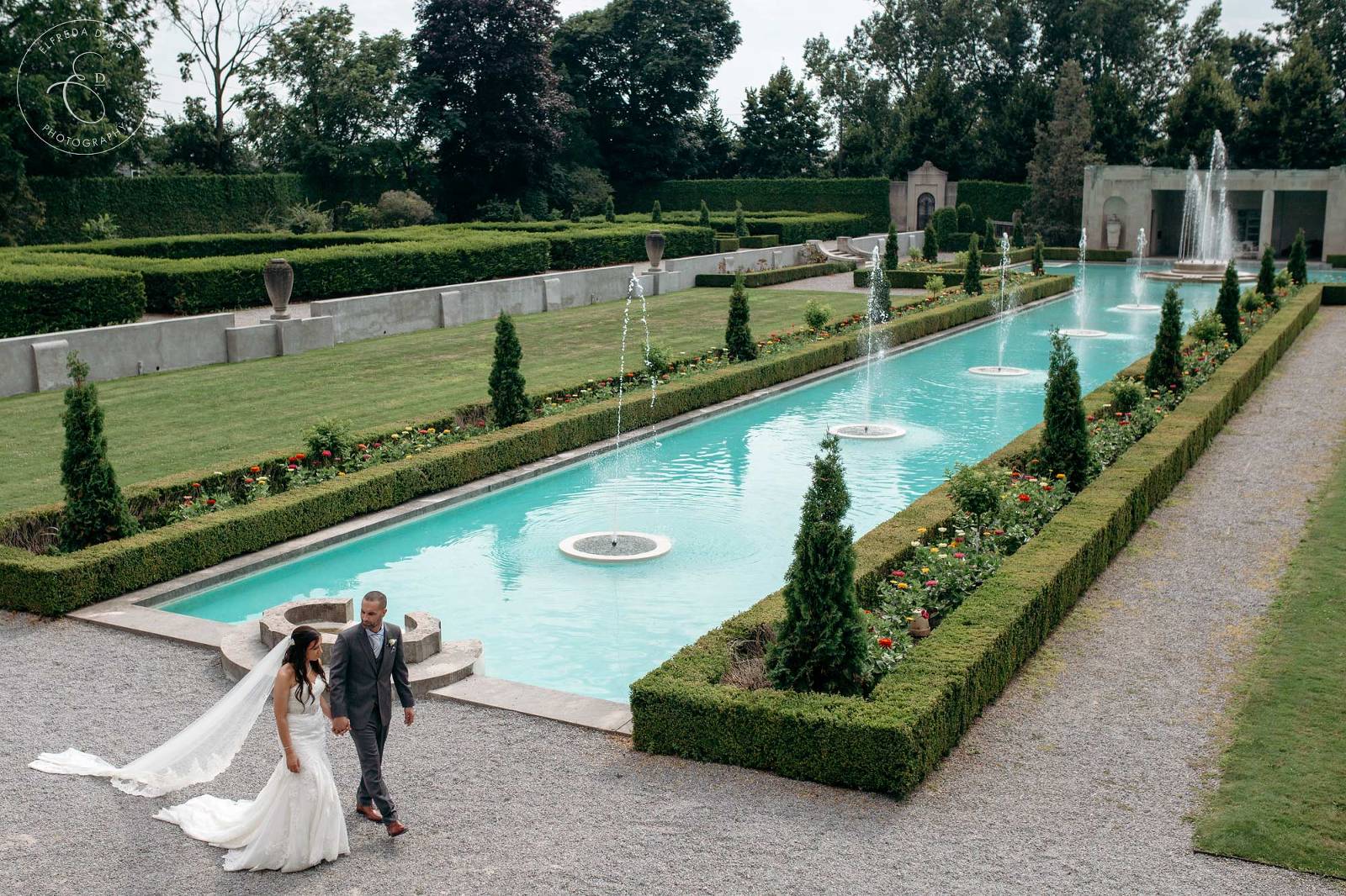 Bride and groom walk next to the fountain at Parkwood estate