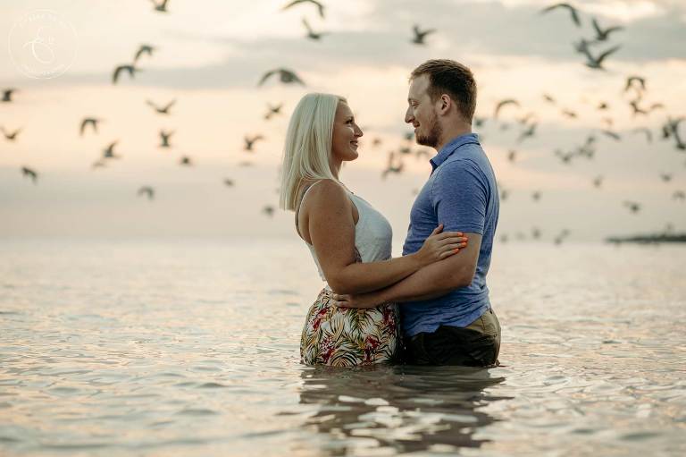 Couple standing in water during sunset