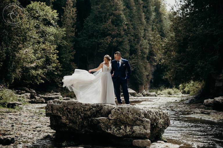 Bride and Groom standing on a rock in the middle of Elora River