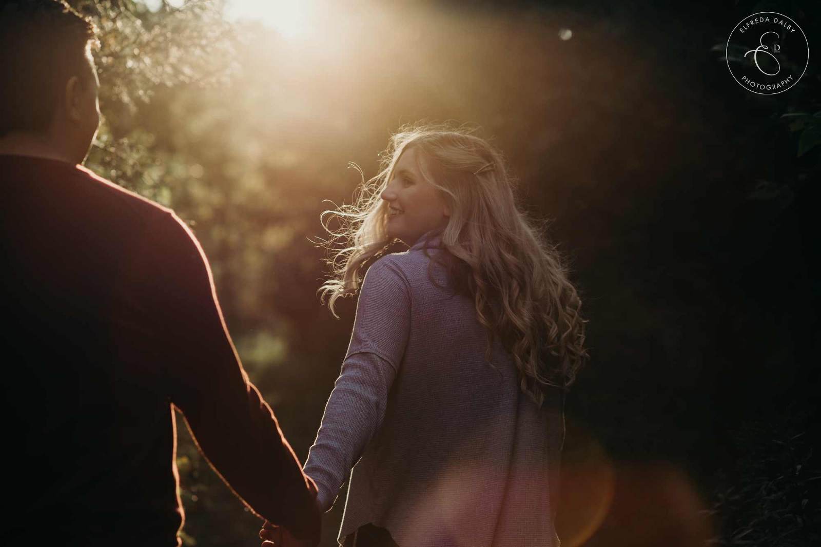 Girl lead guy in path with golden soft light in background
