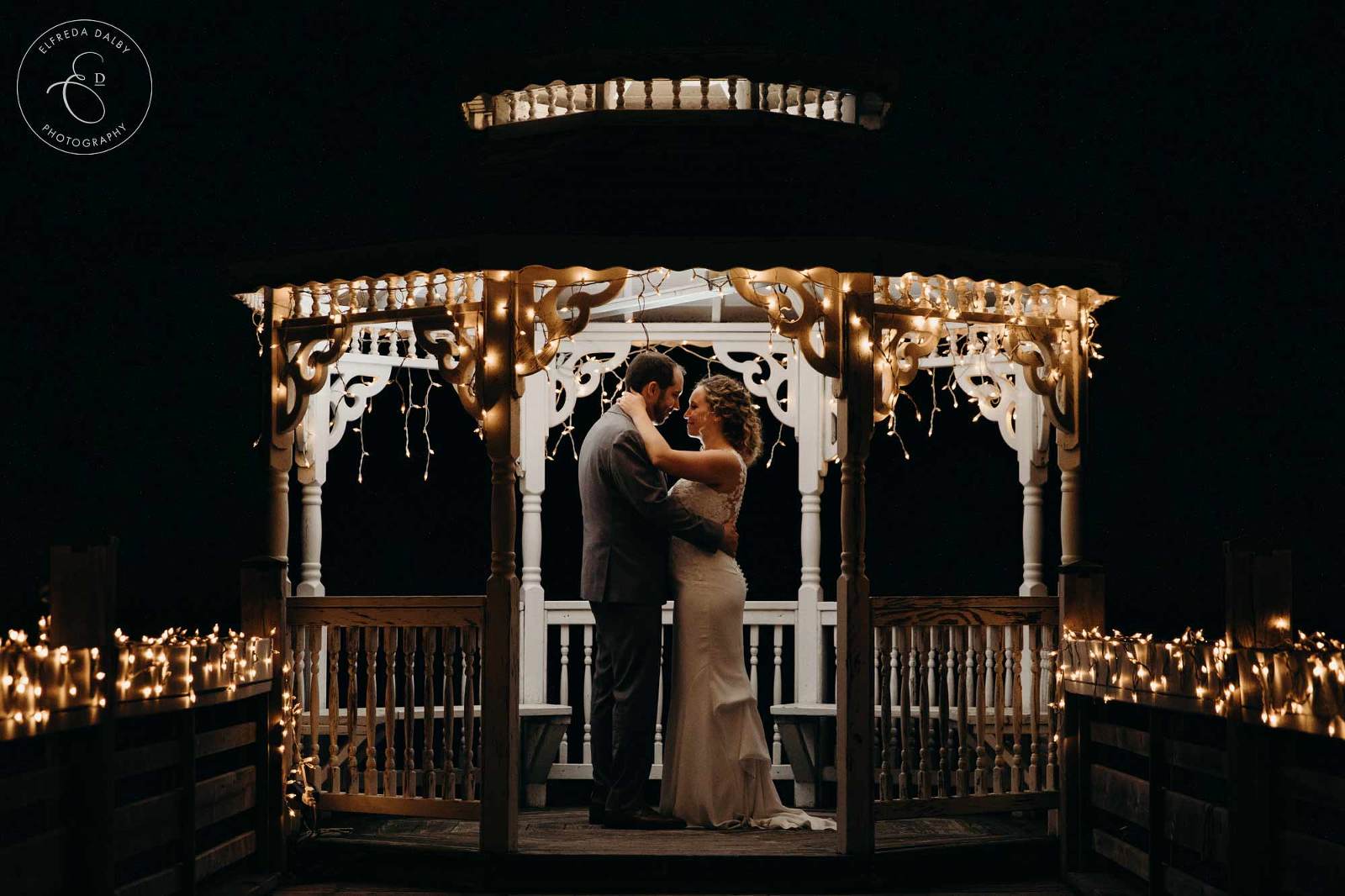 Wedding couple standing in a lit up gazebo
