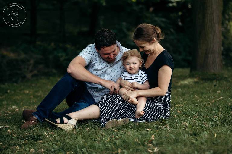 Mom and Dad sits with their baby on the grass