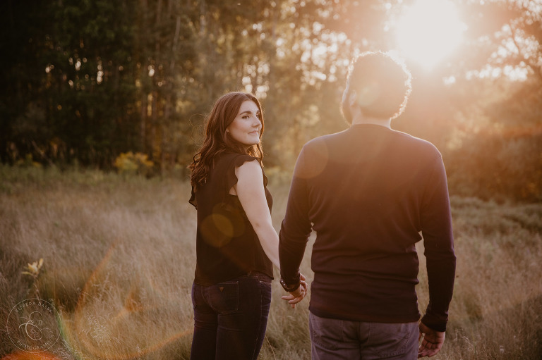 Couple walking through a field during golden hour