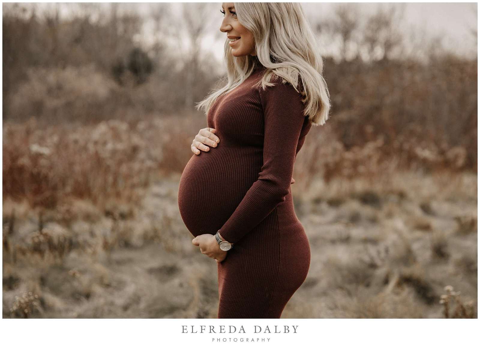Beautiful blond mom holding her tummy during maternity session