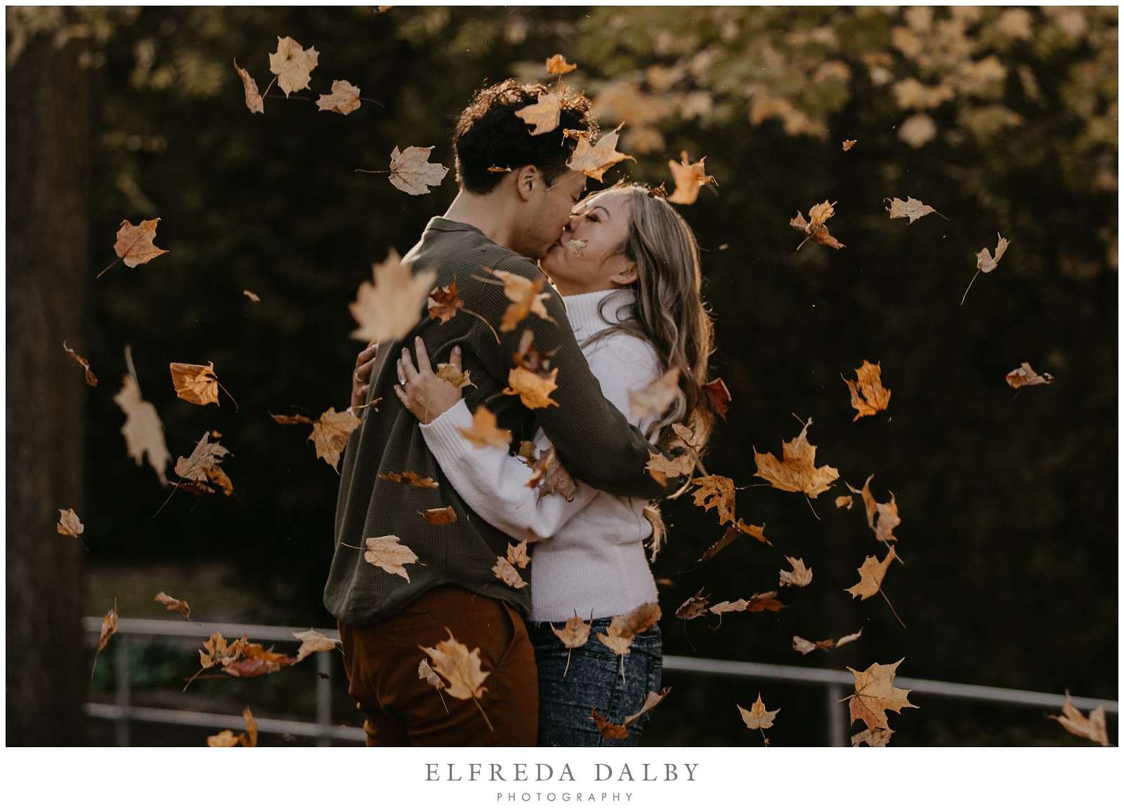 Engaged couple kissing in fallen fall leaves