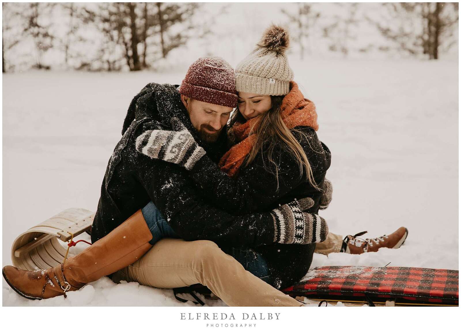 Couple sitting on a sled in the snow hugging