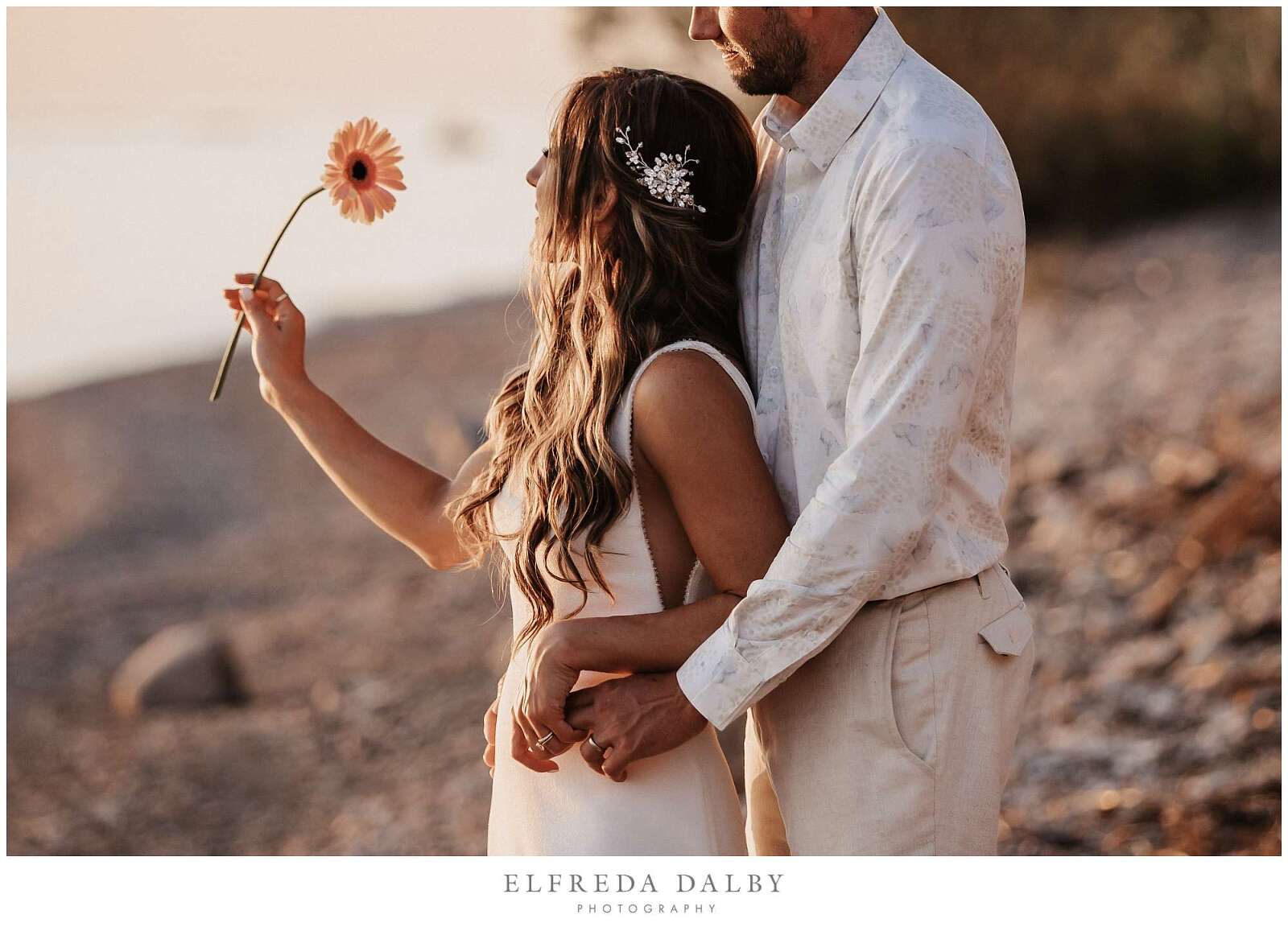 Bride holding a flower on Kincardine beach at sunset