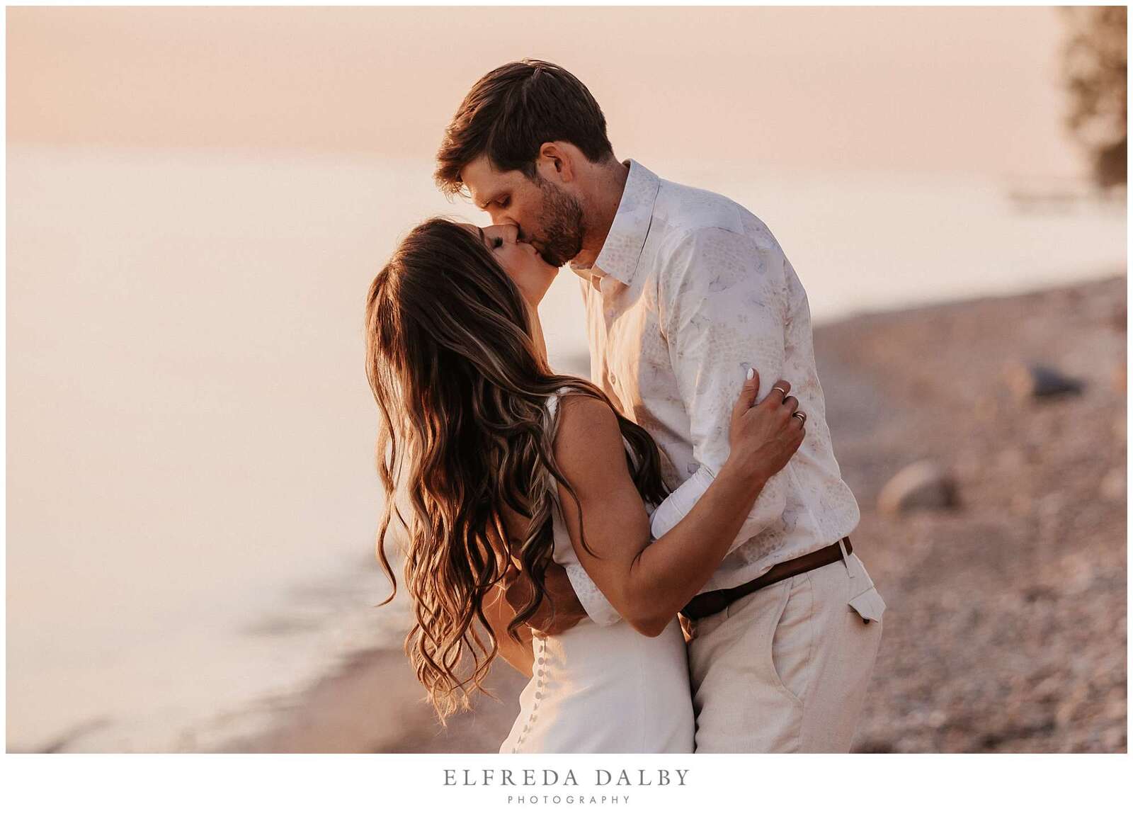Bride and groom kissing on the beach during sunset light
