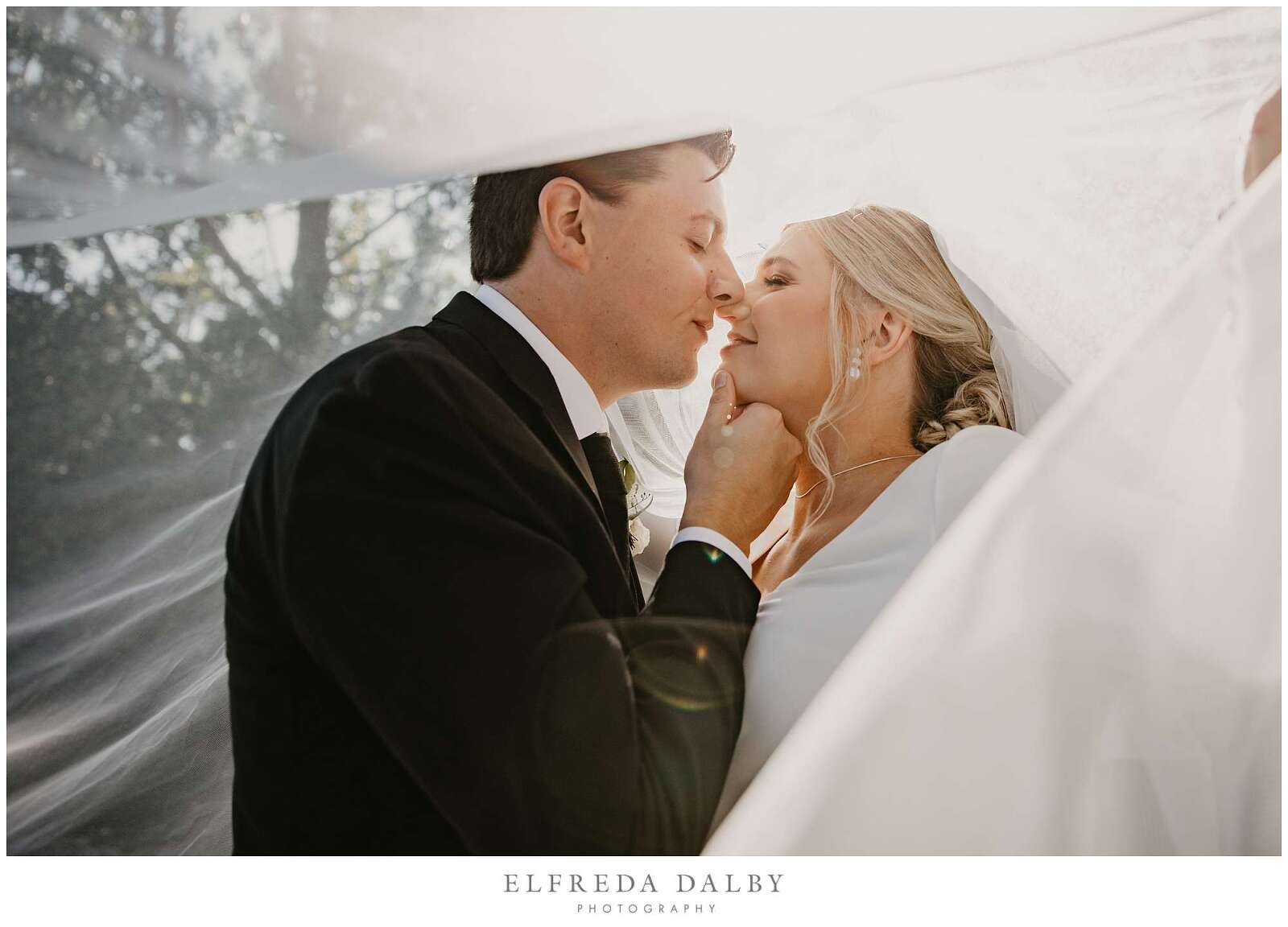 Bride and groom under a veil on a farm