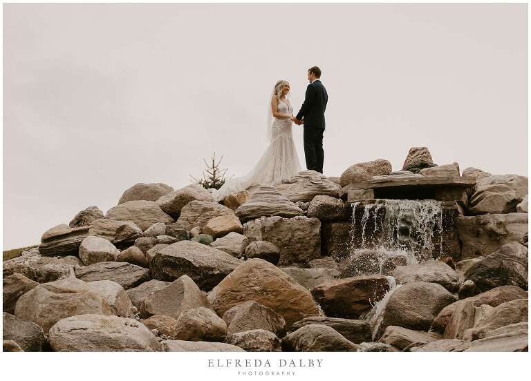 Bride and groom standing at the top of the waterfall at Maple Lane Haven