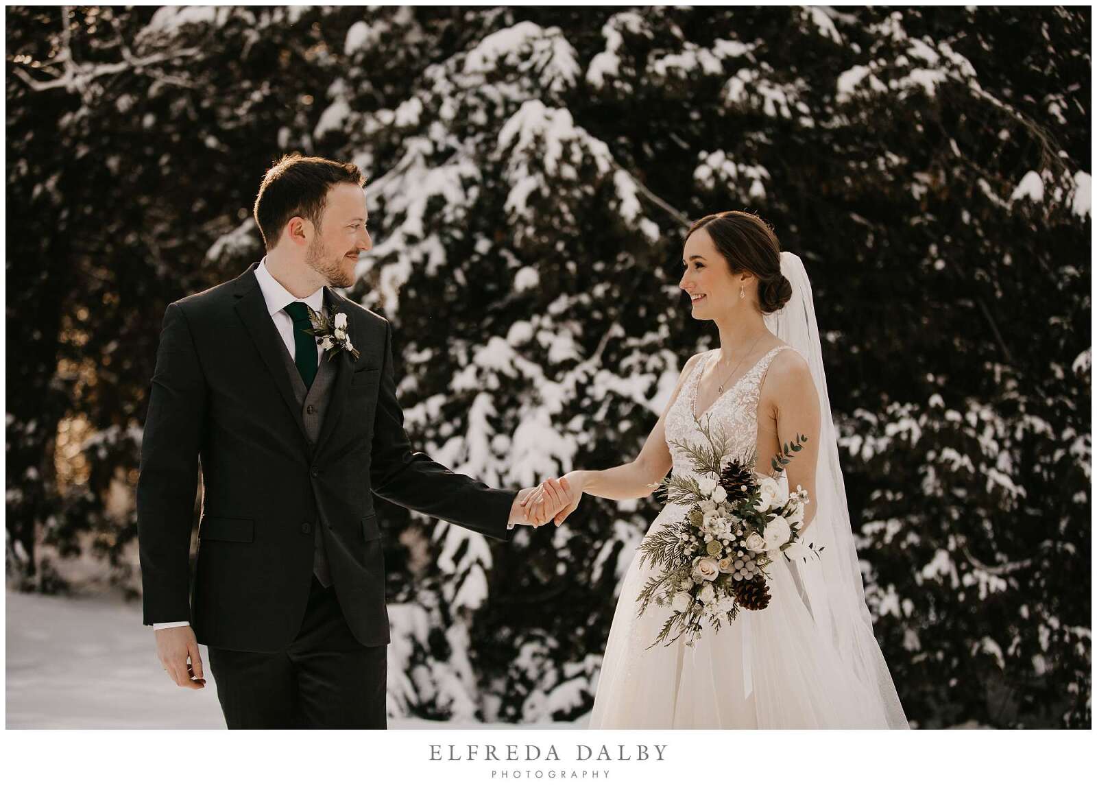 Groom leading his bride through the snow in Elora