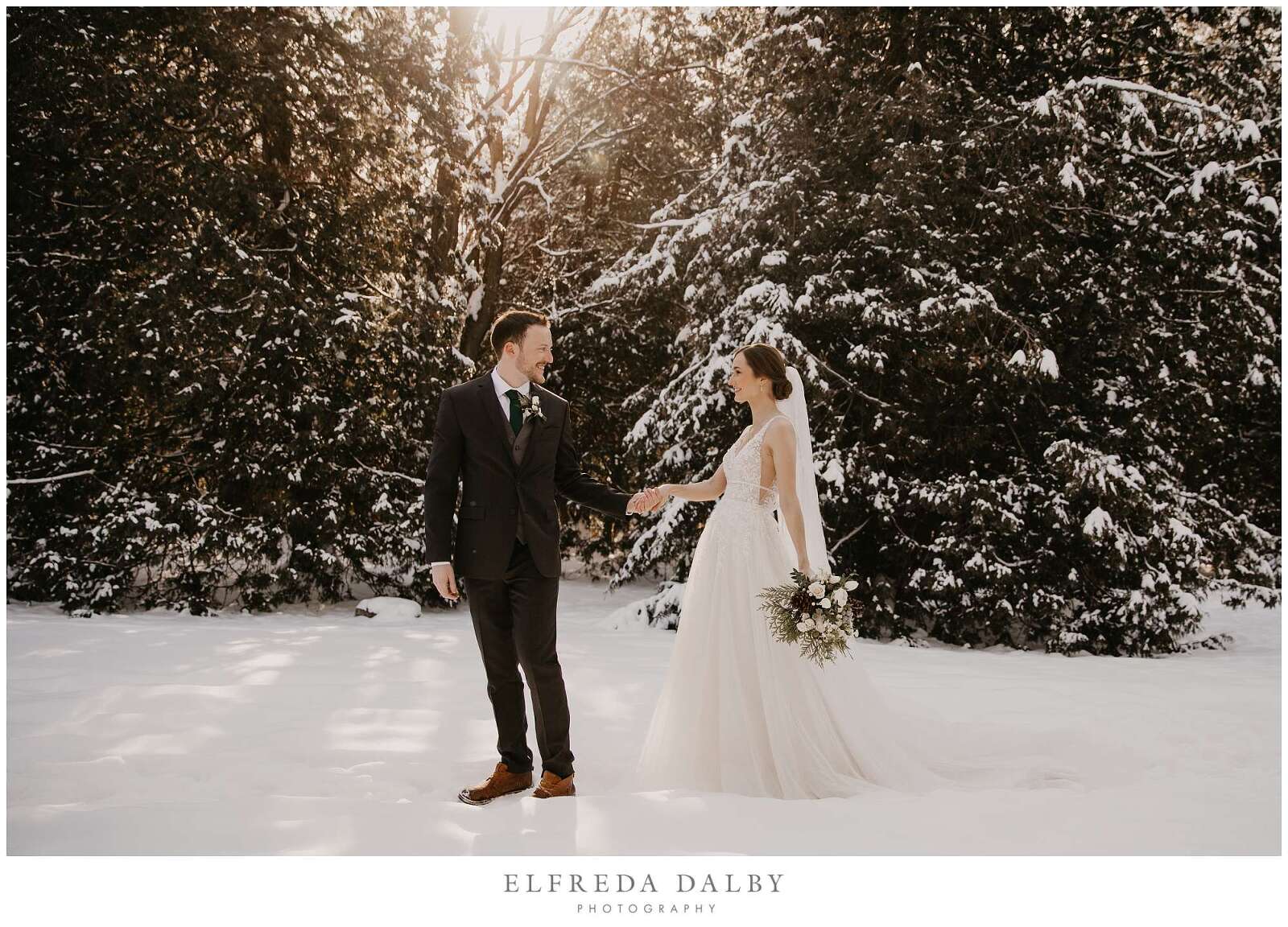 Bride and groom walking in snow during sunset