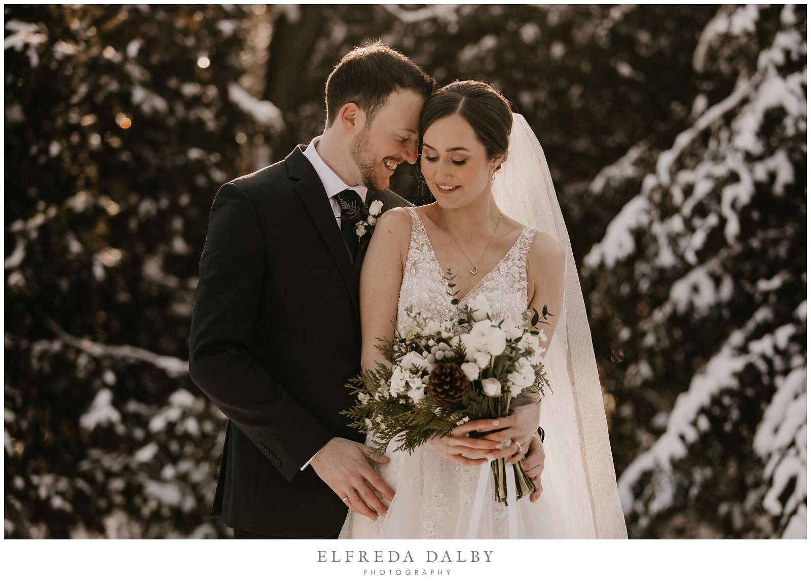 Bride and groom standing in sow with beautiful golden light on them