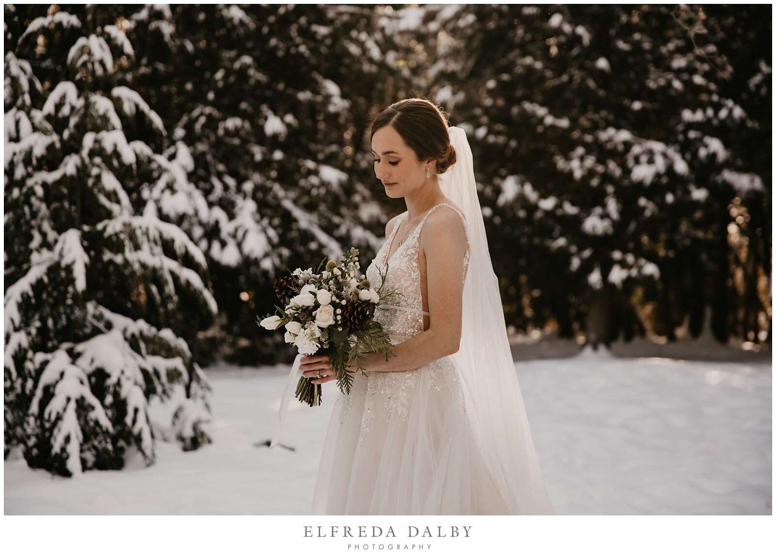 Winter bride looking at her flowers in the snow
