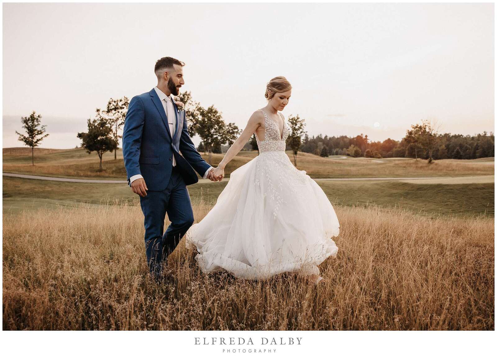 Bride and groom walking through a grassy field at Whistle Bear Golf Club