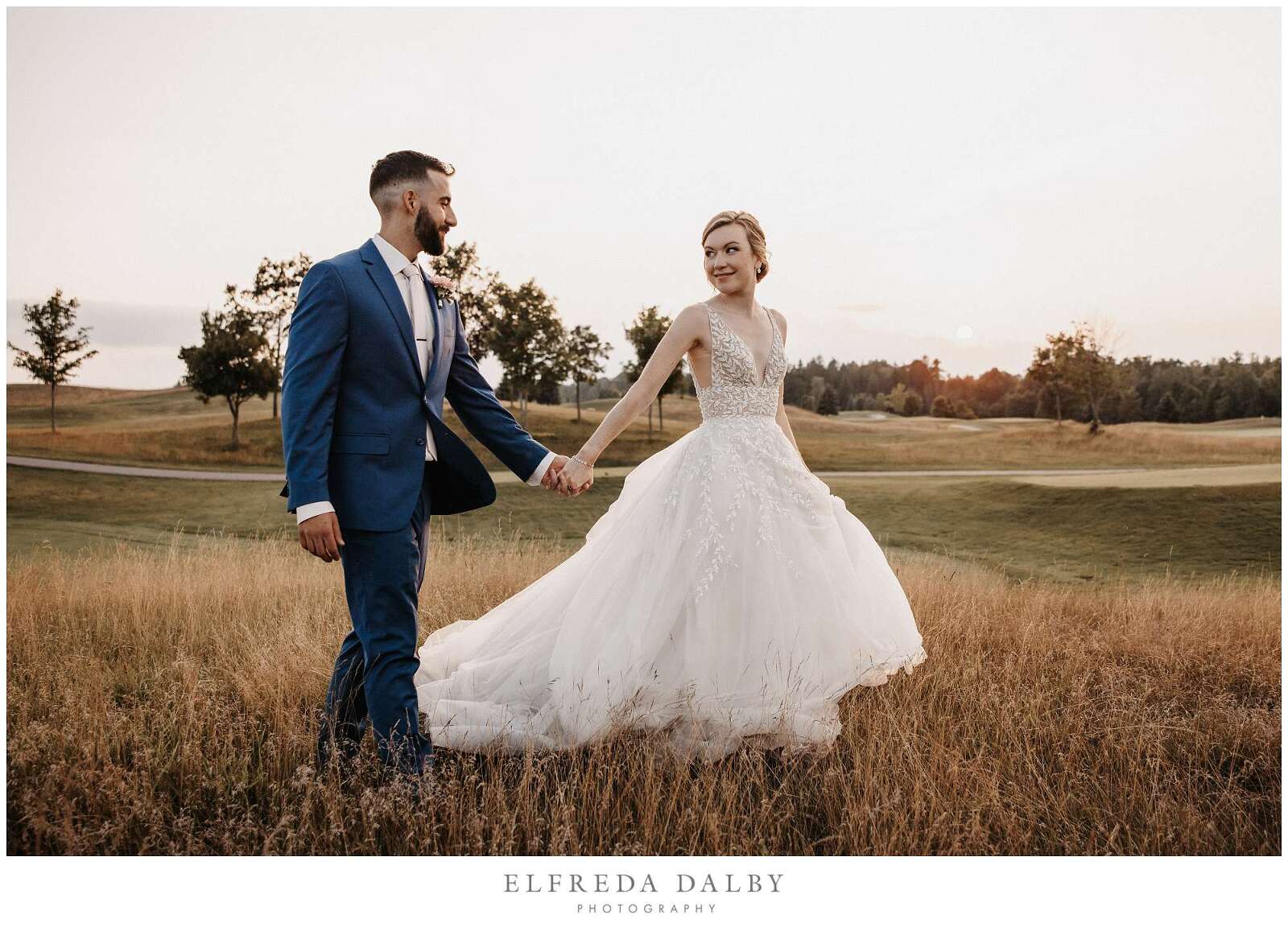 Bride and groom walking through a grassy field at Whistle Bear Golf Club