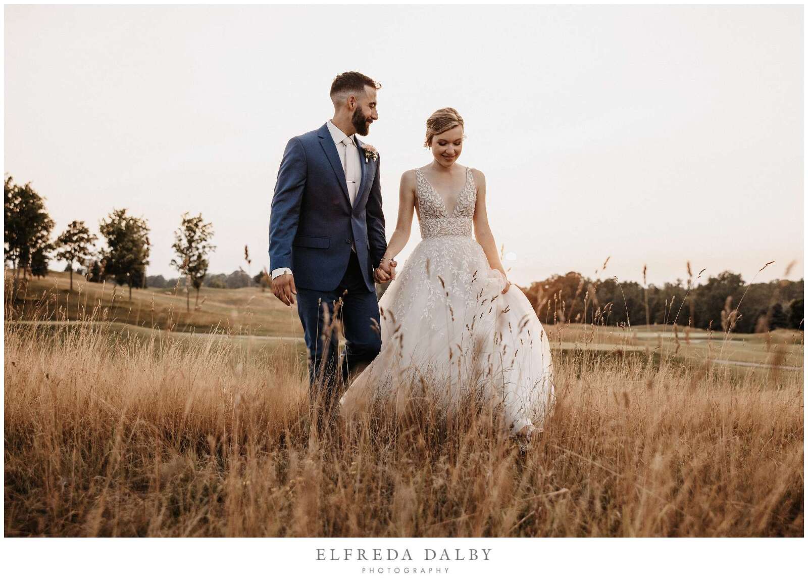 Bride and groom walking through a grassy field at Whistle Bear Golf Club