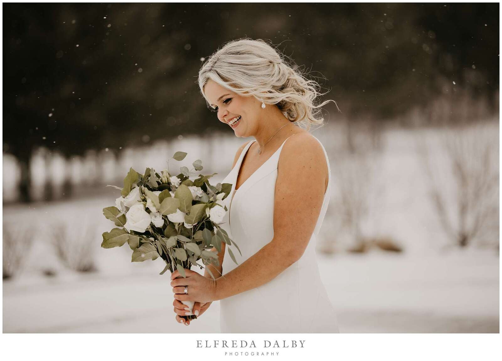 Bride looking at her flowers in the snow at MontHill Golf & Country Club