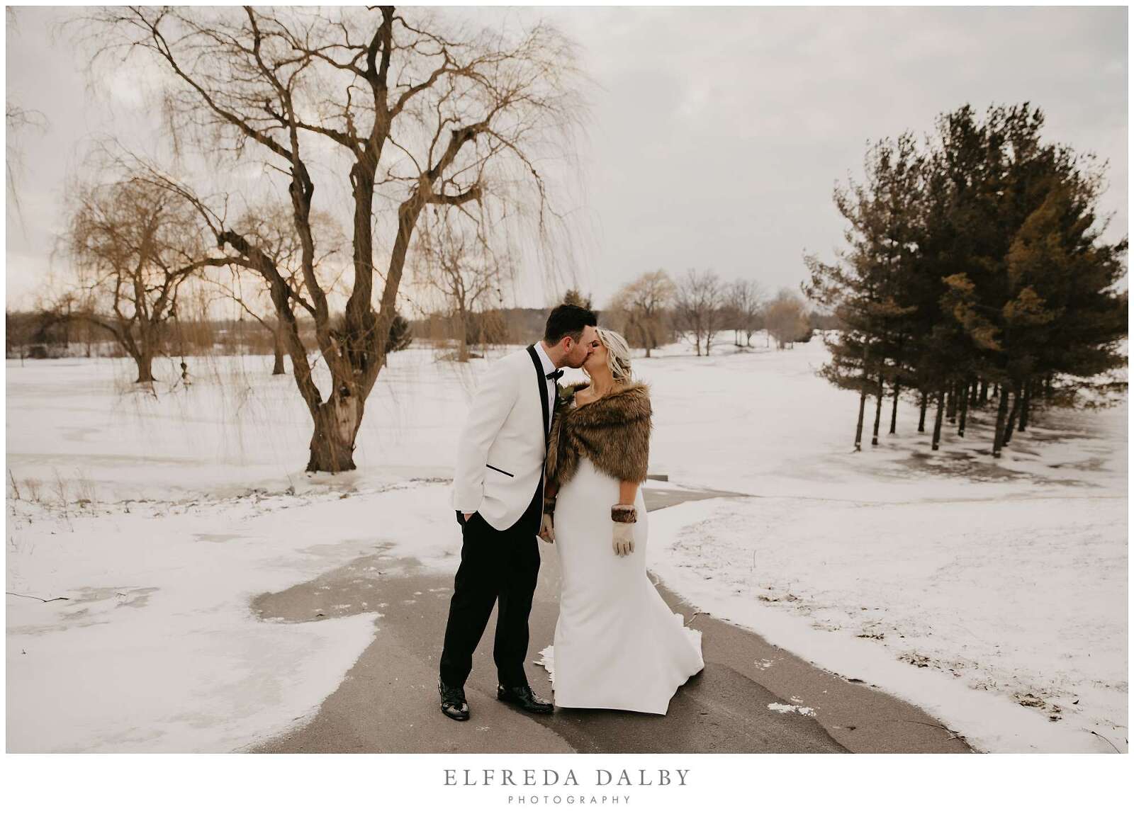 Bride and groom kissing in the snowy path at MontHill Golf & Country Club
