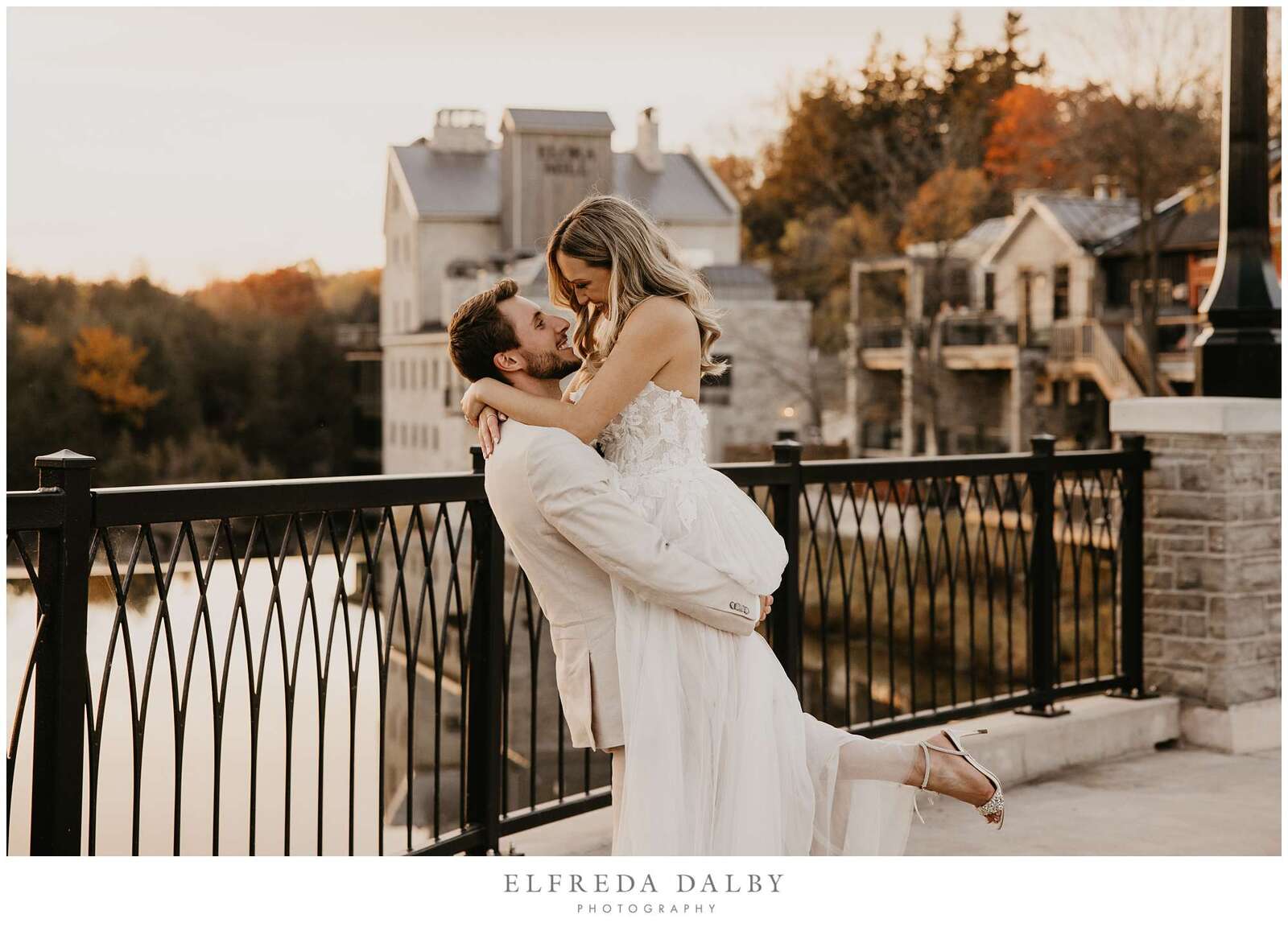 Groom picking up his bride on the bridge at Elora Mill