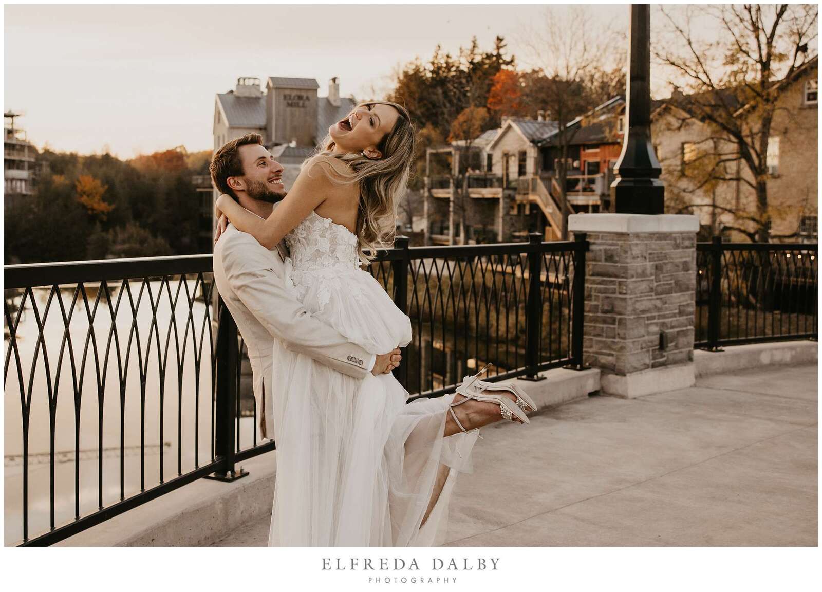 Groom picking up his bride on the walk bridge in Elora