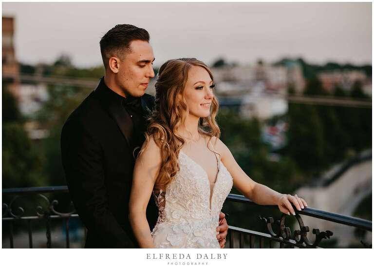 Bride and groom standing on the Juliette balcony during sunset at Cambridge Mill