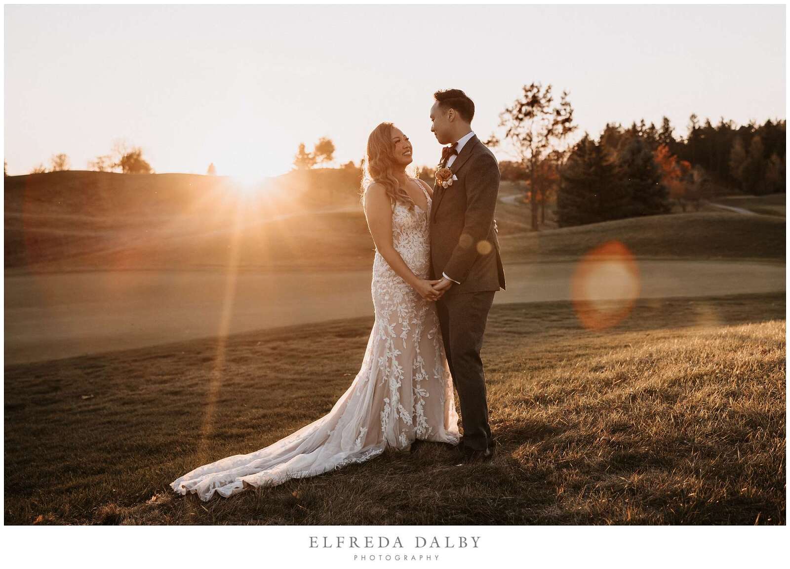 Bride and groom standing in the grassy field at Whistle Bear Golf Club during sunset