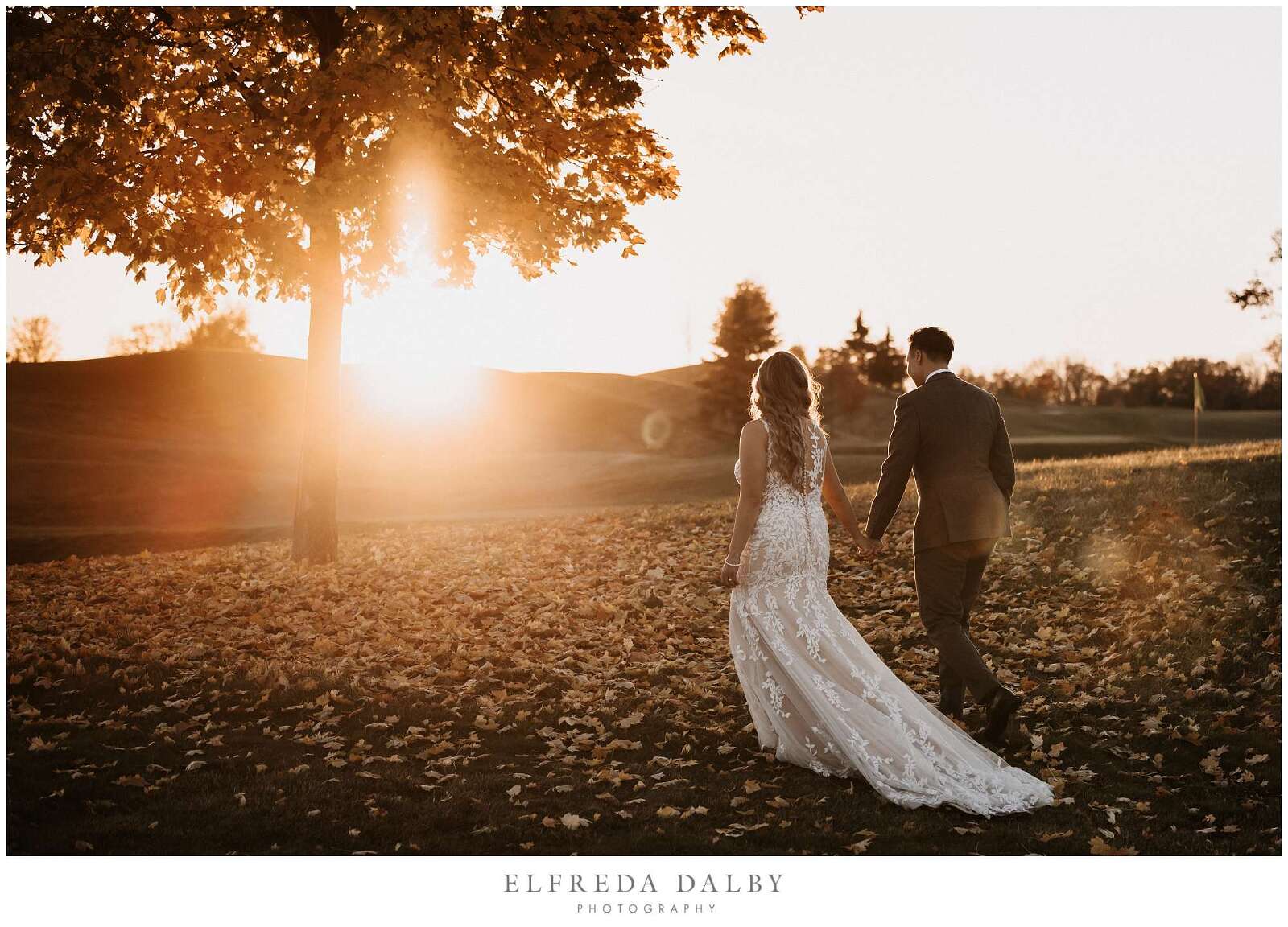 Bride and groom walking over the grassy field during sunset at Whistle Bear Golf Club
