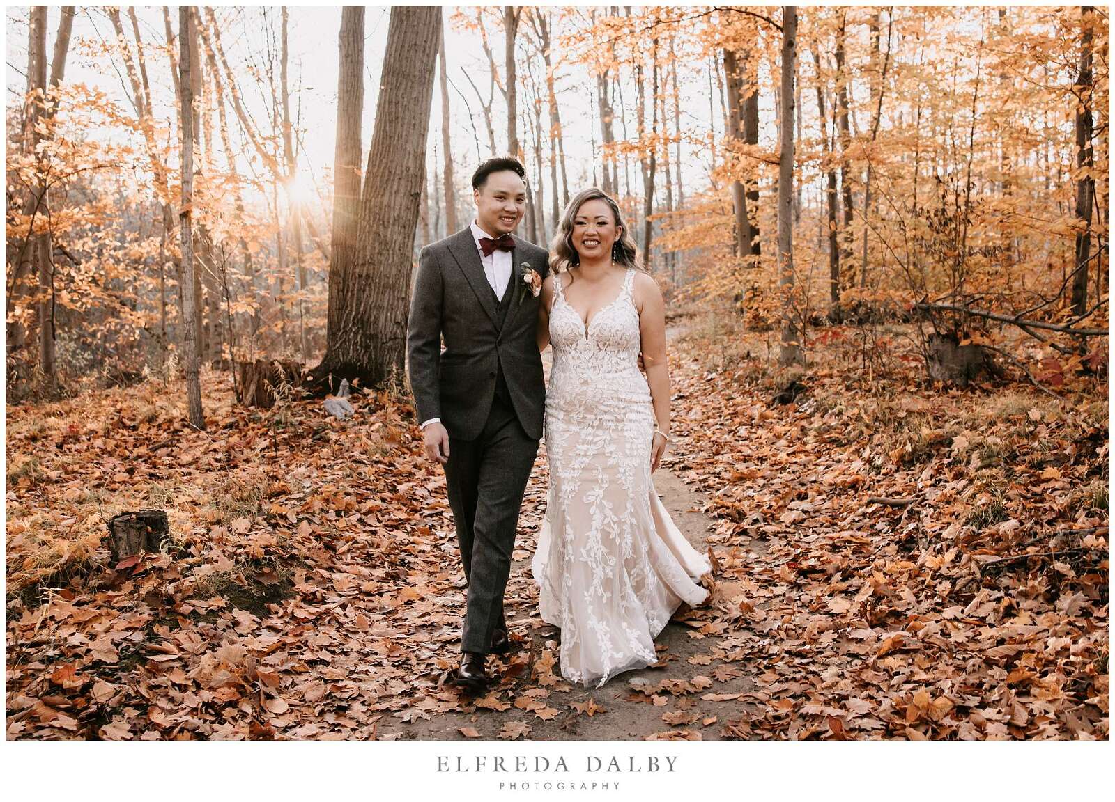 Bride and groom walking in the forest with lots fall leaves at Whistle Bear Golf Club